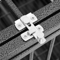 Close-up of the two metal latches on the hinged door of the roofed steel dog crate