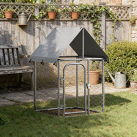 Compact outdoor dog kennel with roof set up on grass in a garden, galvanised steel frame with mesh sides